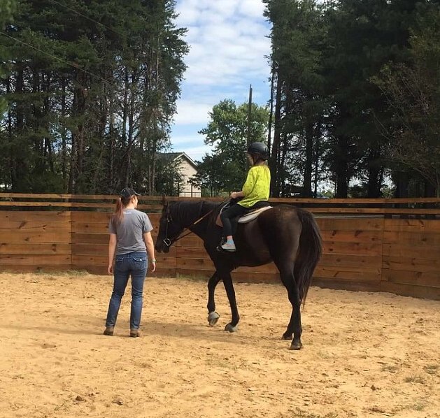 Instructor walking beside a girl on a horse