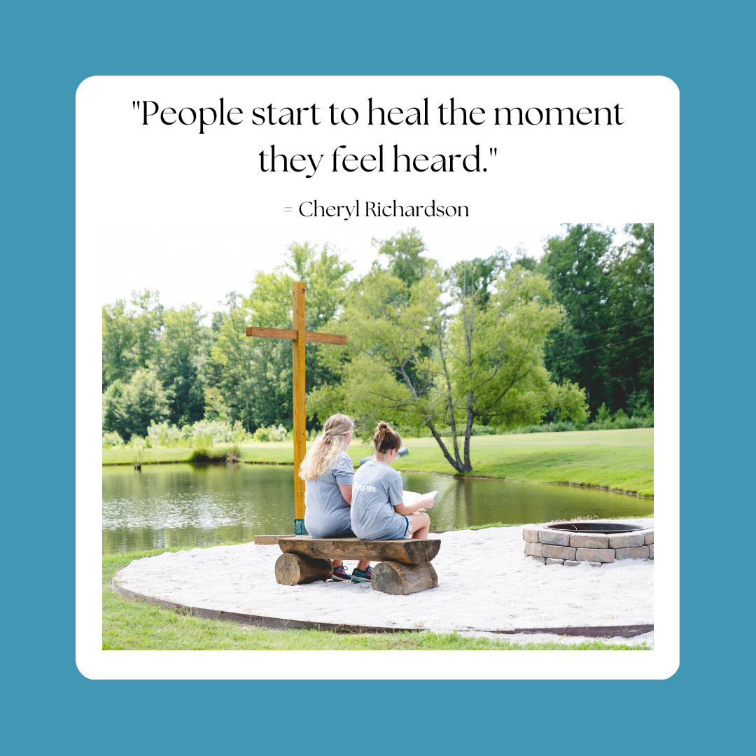 "People start to heal the moment they feel heard" - Cheryl Richardson. Text above an image of two girls sitting and reading beside a lake with a cross beside it.