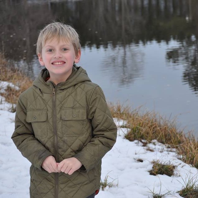 Boy standing in front of a lake in the winter