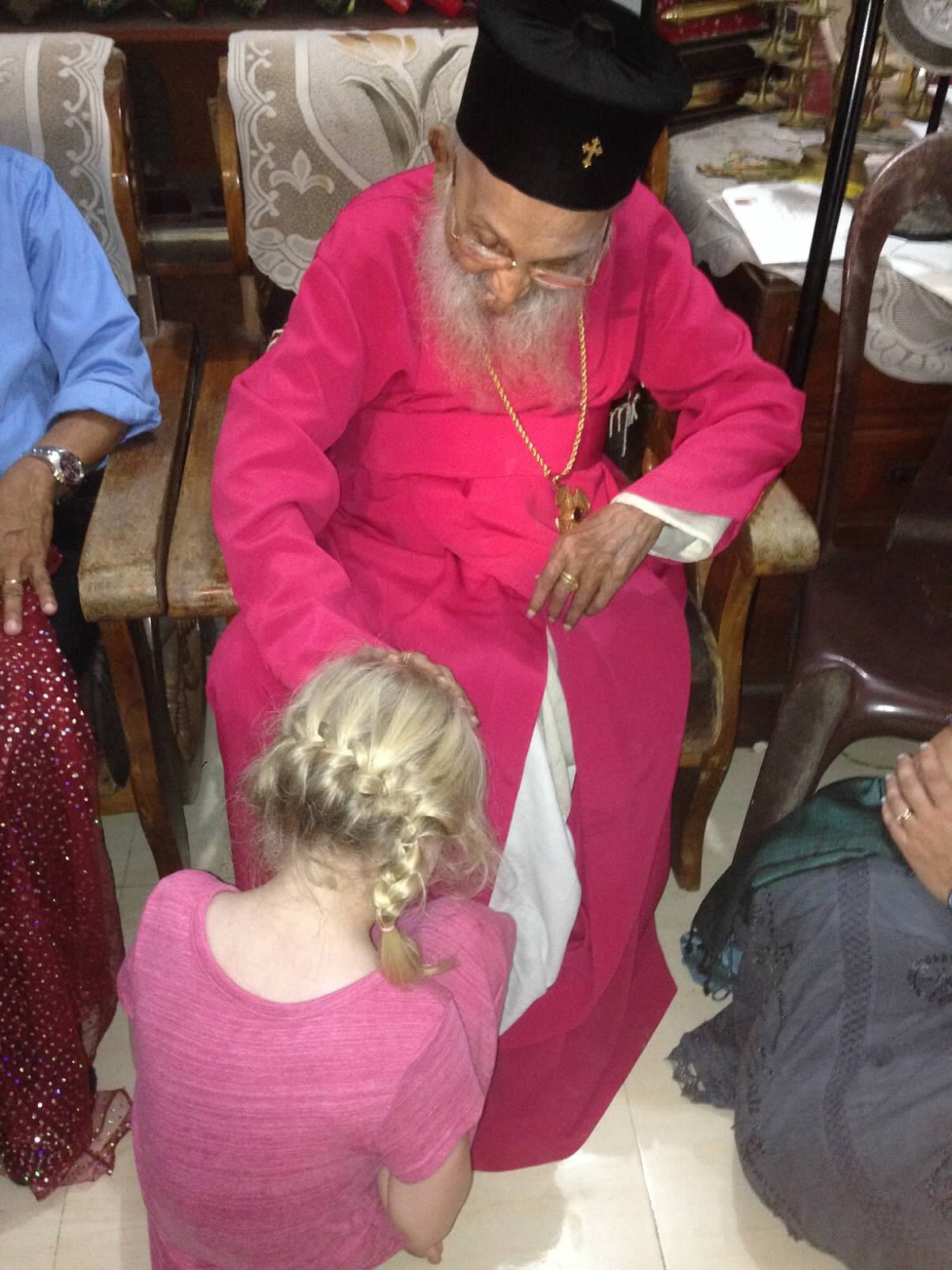 Child sitting in front of Indian Rev. Father